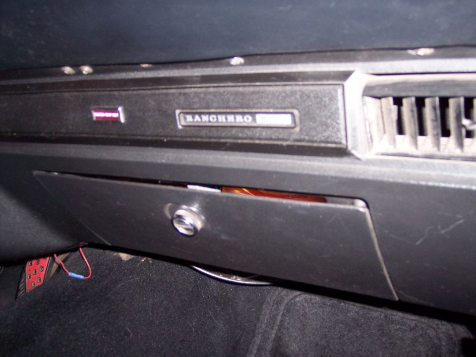 Black dashboard with chrome RANCHERO nameplate above a partly open glove box