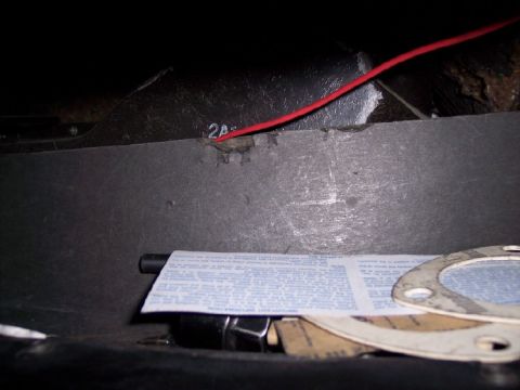 1972 Ford Ranchero - A red wire runs through a dark interior compartment, with a document and gaskets visible.