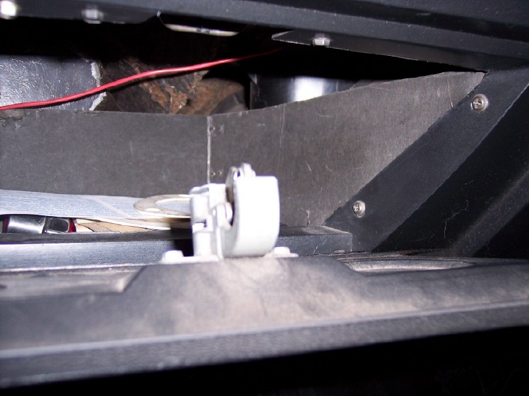 Interior of a vehicle glove box showing a latch mechanism and some papers