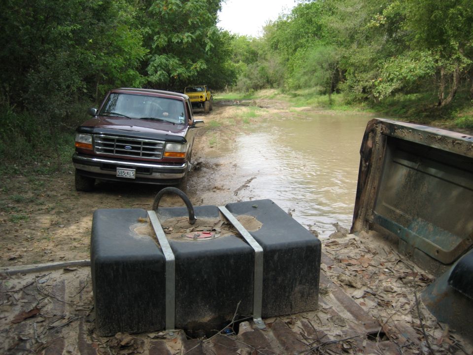 Brown 1992 Ford F-150/Bronco and yellow SUV on muddy trail