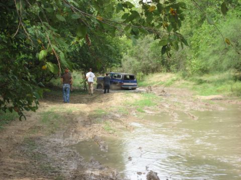 1986 Ford Bronco - Off-road vehicle attempts to navigate a muddy trail, getting stuck in the water.