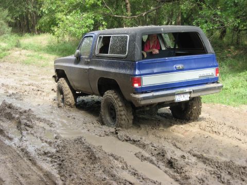 1986 Ford Bronco - This SUV is navigating a muddy trail with two people visible inside.