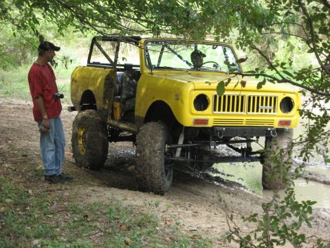 1986 Ford Bronco - Modified International Harvester Scout II navigating muddy terrain with a person observing.