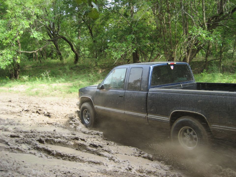 Pickup truck driving through a muddy trail in the woods