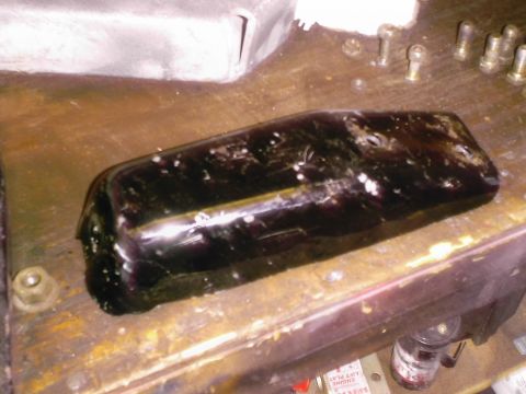 1985 Ford Bronco - An automotive part sits on a workbench with various tools and hardware nearby.