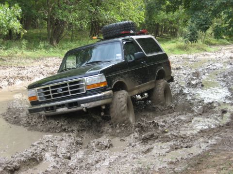 1986 Ford Bronco - This black Ford Bronco navigates a challenging mud obstacle.