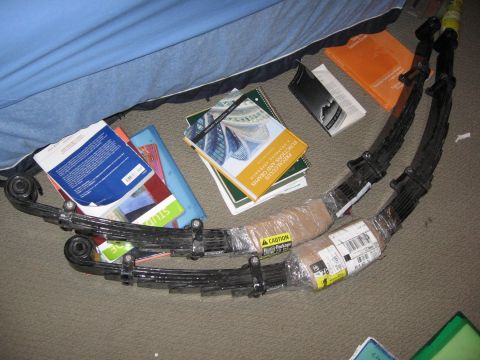 1974 Ford F-100 - Leaf springs and various books are laid out on a carpeted surface.
