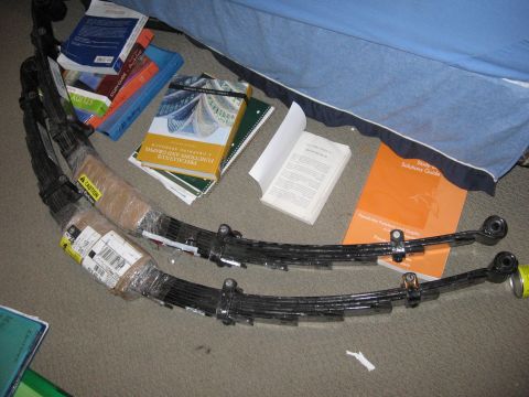 1974 Ford F-100 - Leaf springs and various textbooks are laid out on the floor next to a bed.