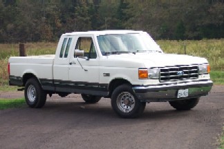 1991 Ford F-150 - A white 1991 Ford F-150 pickup truck is shown from a 3/4 front angle on a paved surface.