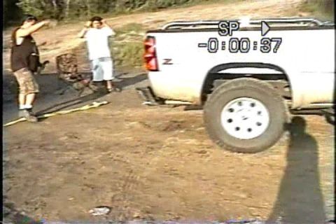 1989 Ford Bronco - A white pickup truck is viewed from the rear on a dirt lot with two people nearby.