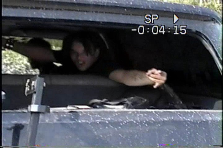 Interior view of a vehicle with two people visible through the window. Timestamp overlay reads -0:04:15