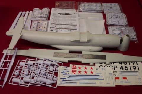 1998 Ford Crown Victoria - A collection of unassembled model airplane parts and decals are spread out on a red surface.