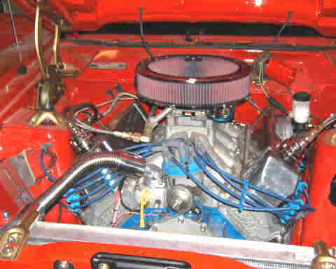 1967 Ford Ranchero - Close-up view of a modified V8 engine in a red vehicle's engine bay.