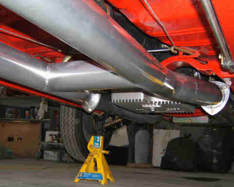 1967 Ford Ranchero - A close-up view of the undercarriage reveals a dual exhaust system supported by a yellow jack stand.