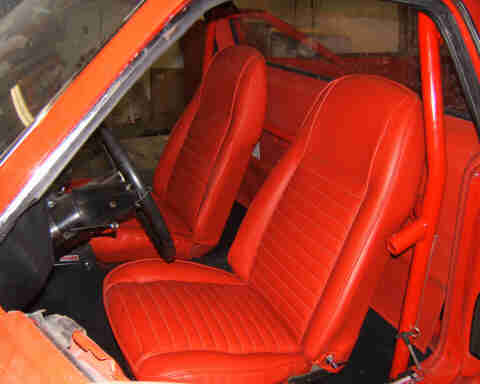 1967 Ford Ranchero - Interior of a red car with bucket seats and a roll cage visible.