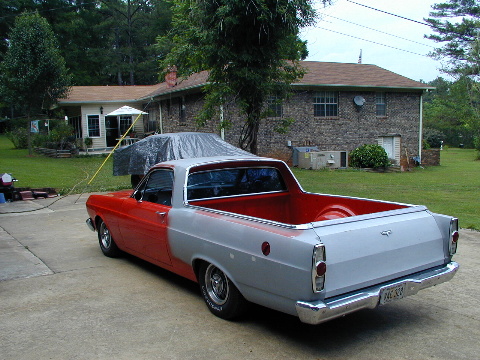 1967 Ford Ranchero - 1967 Ford Ranchero in primer gray and red, parked in front of a brick house.