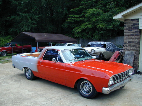 1967 Ford Ranchero - A two-tone Ford Ranchero is parked outside a garage, with other vehicles and a carport visible in the background.
