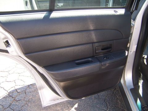 2003 Ford Crown Victoria - The interior door panel of a 2003 Ford Crown Victoria shows a black plastic finish with horizontal ridges.