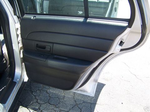 2003 Ford Crown Victoria - The interior of a car's rear door is shown, with black door paneling and a view of the exterior.