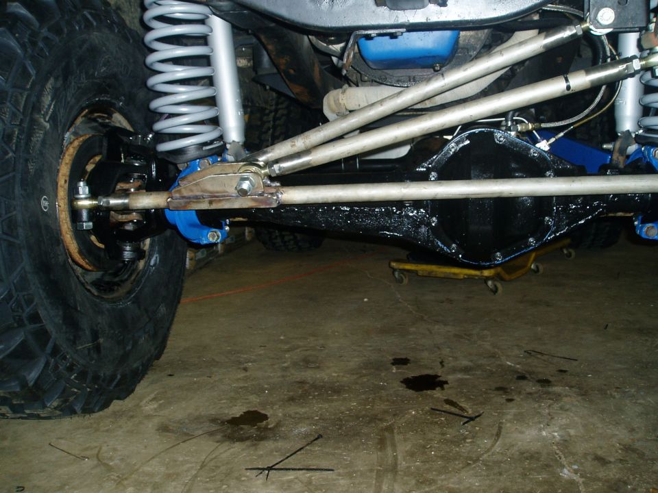 Close-up of a vehicle's front axle, suspension, and differential with large tires