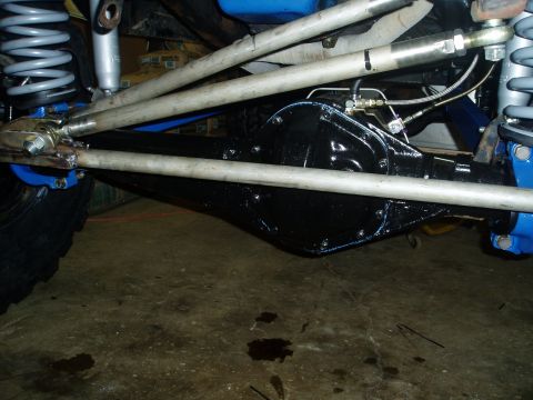 1969 Ford Bronco - Close-up view of a vehicle's rear axle assembly, showing suspension linkages and brake lines.