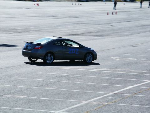 2001 Mercury Grand Marquis - A dark grey coupe with blue racing numbers is seen on an asphalt course during an event.