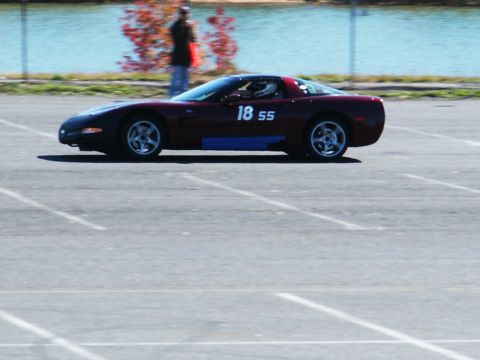 2001 Mercury Grand Marquis - A red sports car with racing numbers 18 55 is seen on a track next to a body of water.