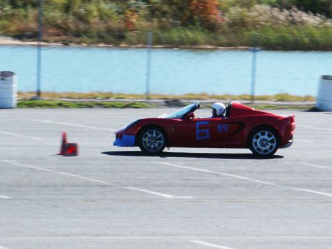 2001 Mercury Grand Marquis - A red convertible sports car with a blue front bumper navigates a track, indicated by a cone and painted lines.