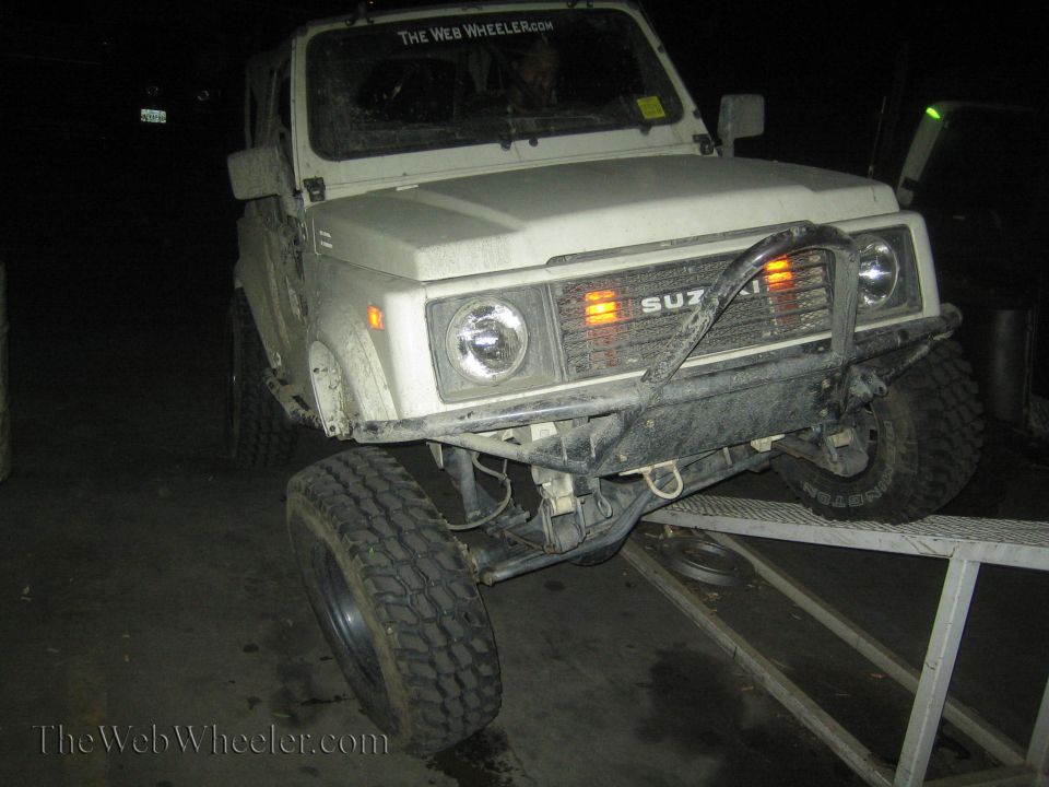 White 1987 Suzuki Samurai on an RTI ramp, front-left tire elevated