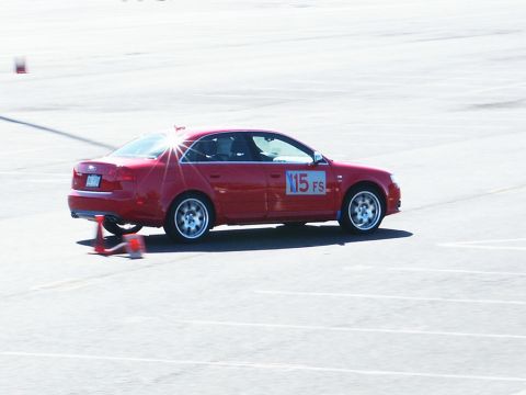 2001 Mercury Grand Marquis - A red sedan navigates a course marked by orange cones, displaying a racing number on its door.