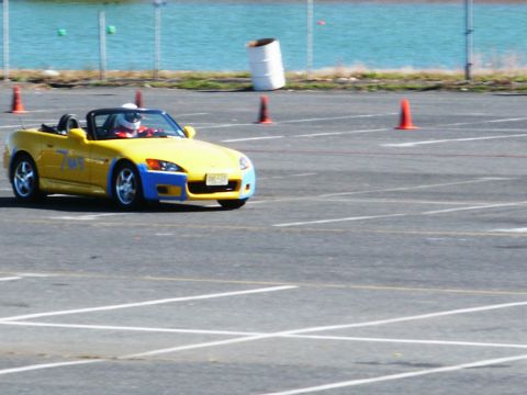 2001 Mercury Grand Marquis - A yellow convertible sports car navigates a track marked with cones and painted lines.