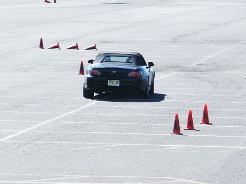 2001 Mercury Grand Marquis - A black convertible sports car is seen from the rear, maneuvering through a course marked by orange traffic cones on a paved surface.