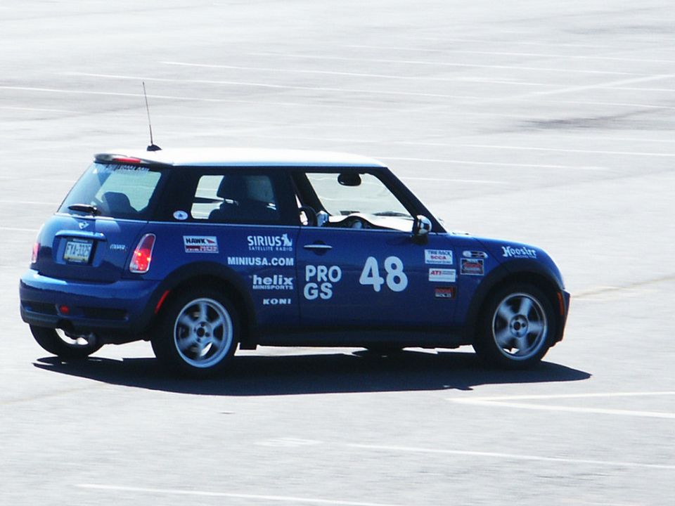 Blue Mini Cooper with racing decals, number 48, and a white roof, seen from the side