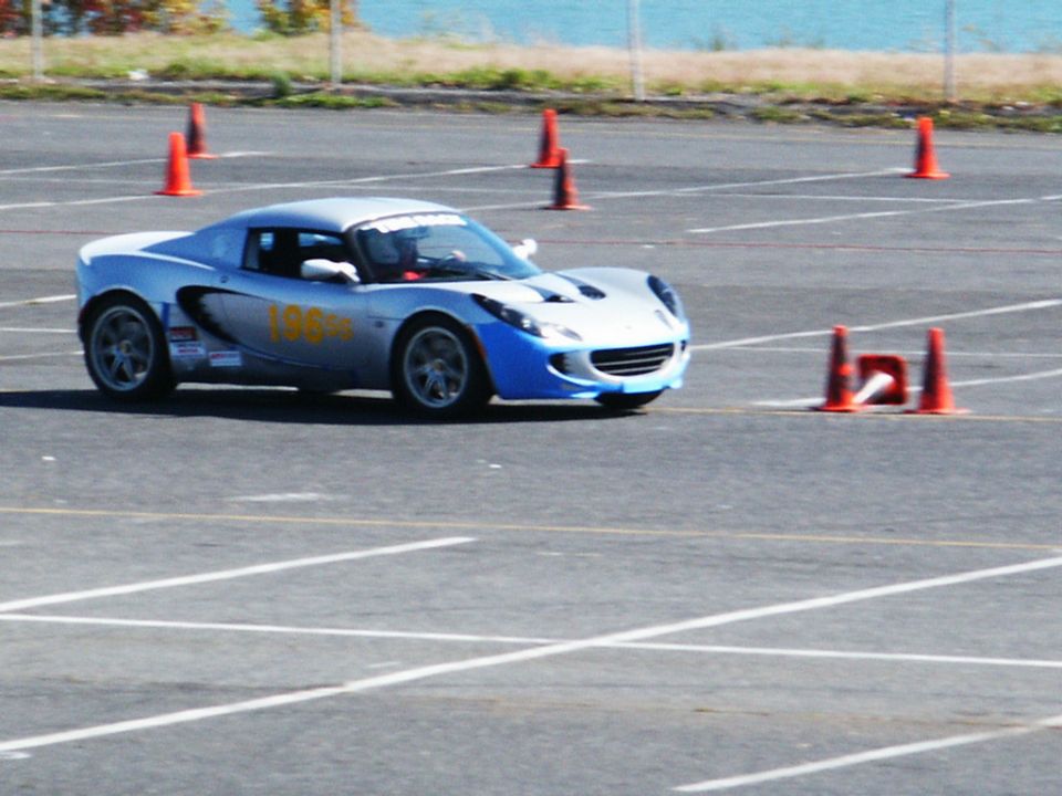 Silver and blue sports car with yellow '198' on the side navigating a cone course