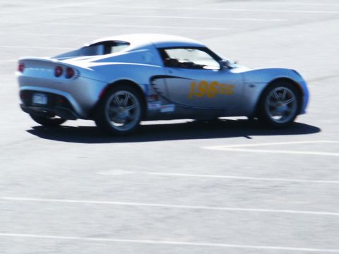 2001 Mercury Grand Marquis - A silver Lotus Elise is captured in motion on a paved surface, displaying racing decals.