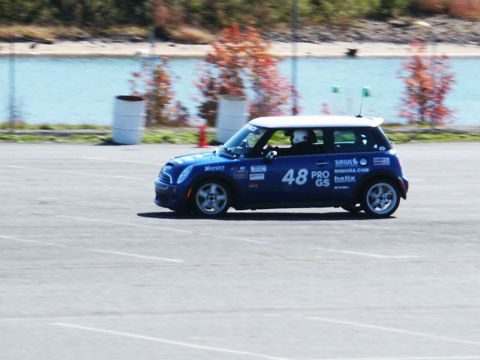 2001 Mercury Grand Marquis - A blue Mini Cooper race car with various sponsor decals is seen on a paved track with a body of water in the background.