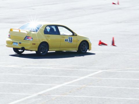 2001 Mercury Grand Marquis - A yellow sedan navigates a course marked by traffic cones on a sunny day.
