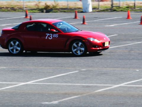 2001 Mercury Grand Marquis - A red sports car with racing numbers navigates a cone course on a sunny day.