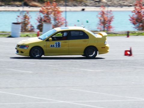 2001 Mercury Grand Marquis - A yellow sedan with racing decals is seen on a track during an event.
