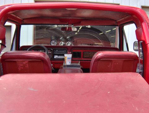 1978 Ford Bronco - The interior of a red SUV is shown, red seats and a dashboard with various gauges and a radio.