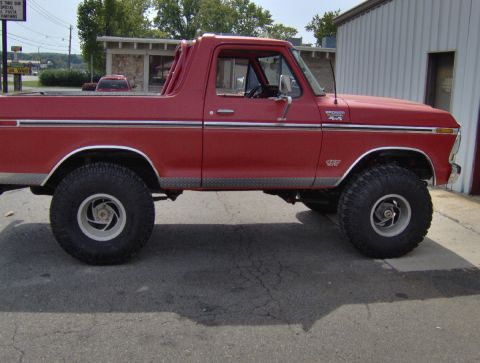 1978 Ford Bronco - Side view of a red 1978 Ford Bronco, showing its diamond plate trim and lifted suspension.