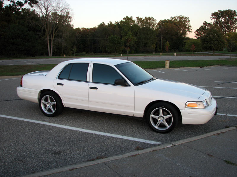 White Ford Crown Victoria sedan side view in an empty parking lot at dusk