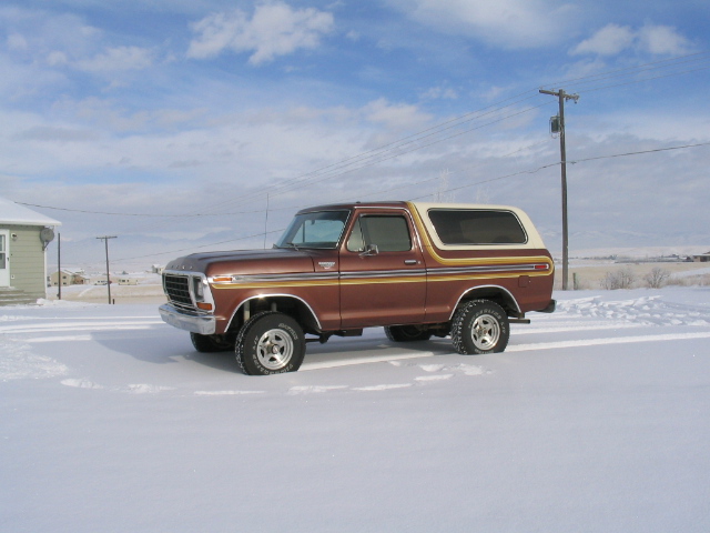 Brown Ford Bronco with white top parked in snow. Side view