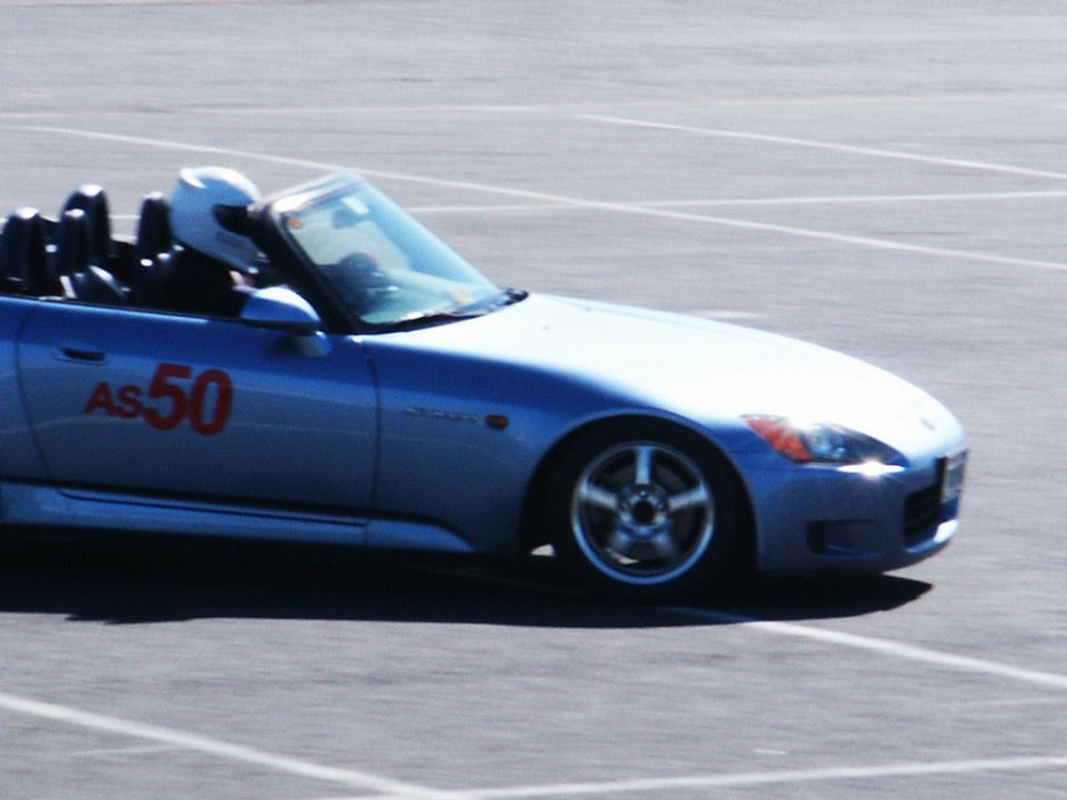 Blue convertible sports car with red racing numbers 'AS 50' on the door, seen from the side at a race track