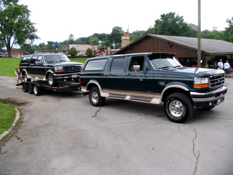1995 Ford C-150 (Centurion Conversions) - Two Ford Bronco SUVs are shown, one being towed on a trailer by the other.