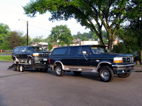 1995 Ford C-150 (Centurion Conversions) - Two dark green Ford C-150 Centurion Conversion SUVs are shown, one loaded onto a trailer.