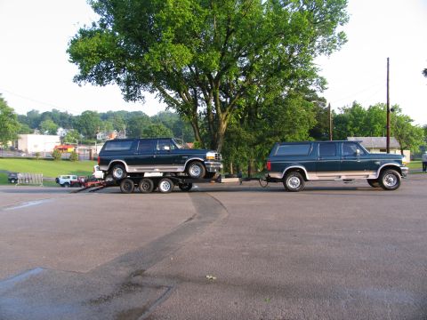 1995 Ford C-150 (Centurion Conversions) - Two extended wheelbase Ford Bronco Centurion Conversions are shown, with one vehicle loaded onto a trailer towed by the second vehicle.