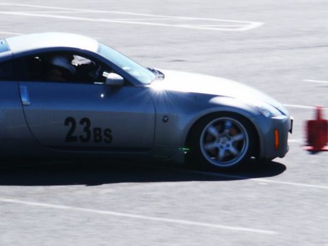 2001 Mercury Grand Marquis - A silver sports car navigates a race track, indicated by the orange cone and racing numbers on its door.