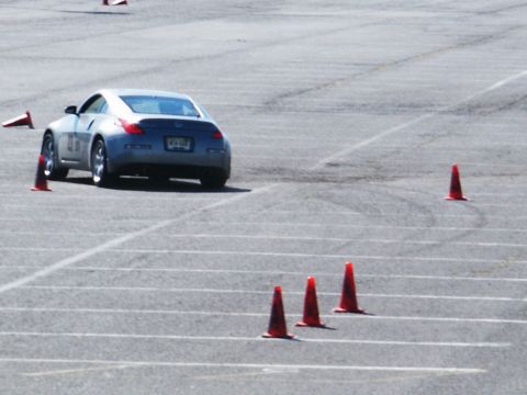 2001 Mercury Grand Marquis - A silver Nissan 350Z navigates a course marked by orange traffic cones on a paved surface.