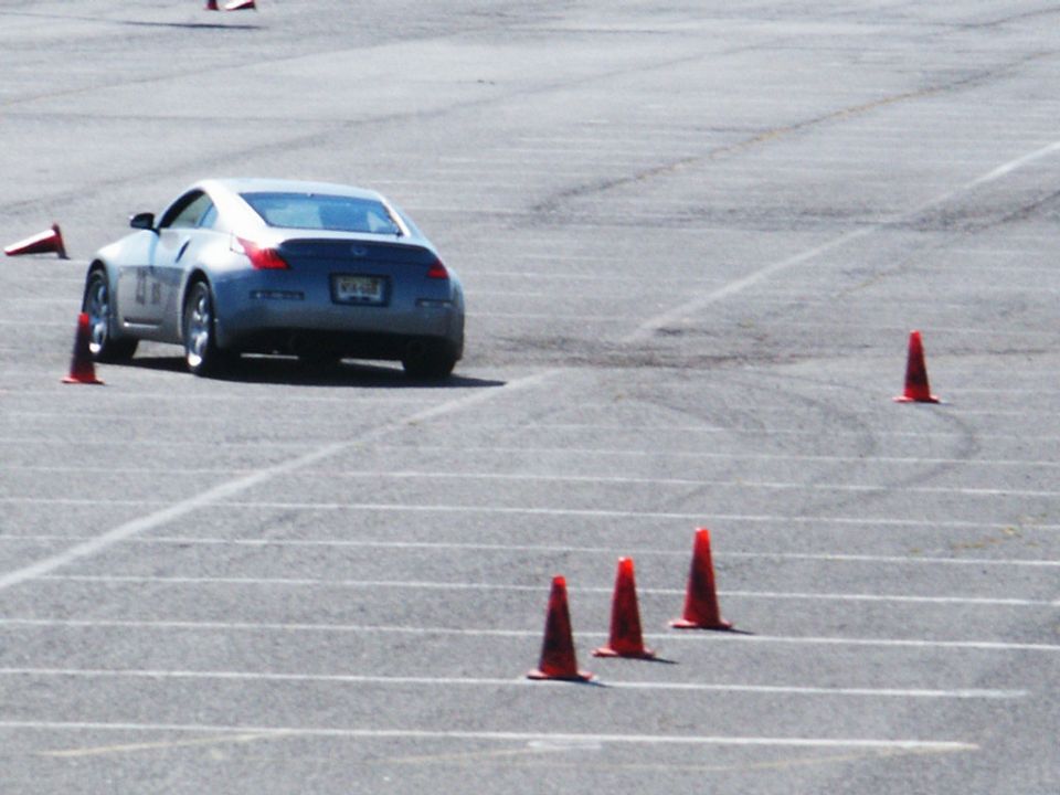 Silver Nissan 350Z with racing number 11 on the door, seen from the rear on a paved track with orange cones
